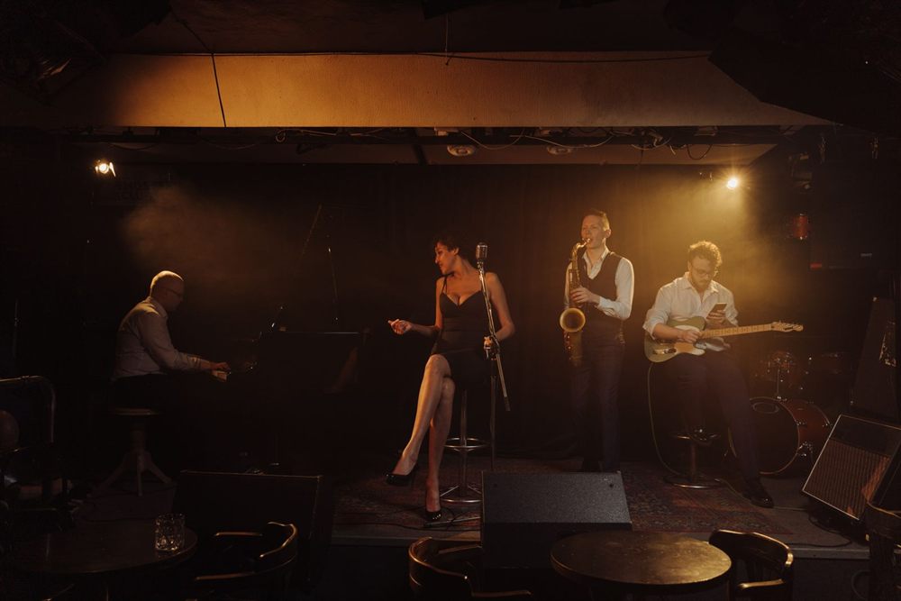 Jazz band with a singer, piano, saxophone and guitar on a small club stage