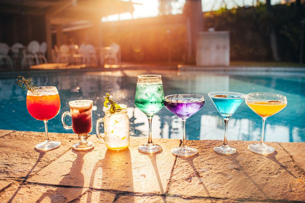 Row of colorful cocktails on a sunny poolside table