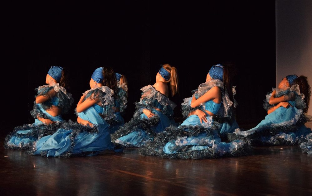 Dancers in blue costumes performing together on stage