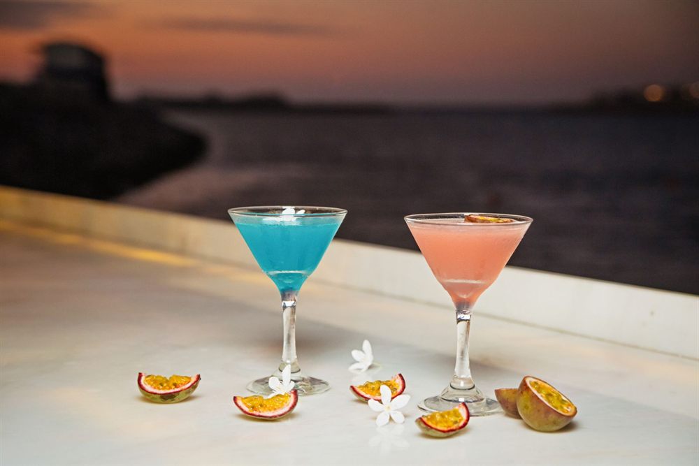 Two martini cocktails on a bar ledge overlooking the sea at dusk