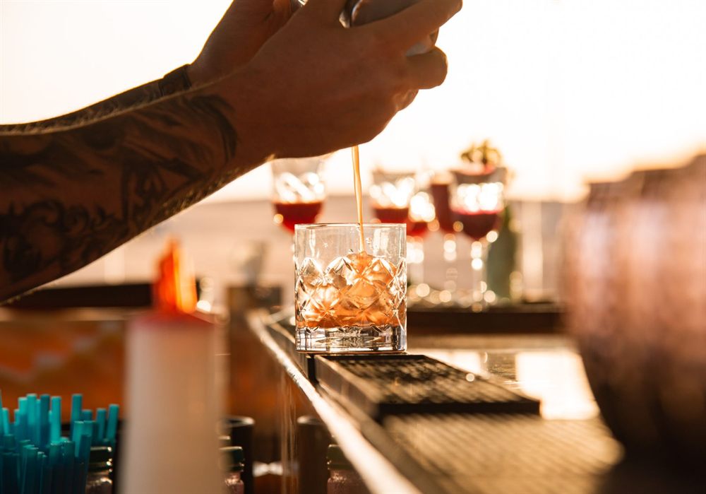 Bartender finishing a cocktail at a bar in sunset light
