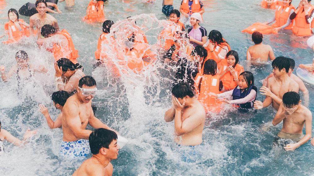 Crowd splashing and laughing at a lively pool party