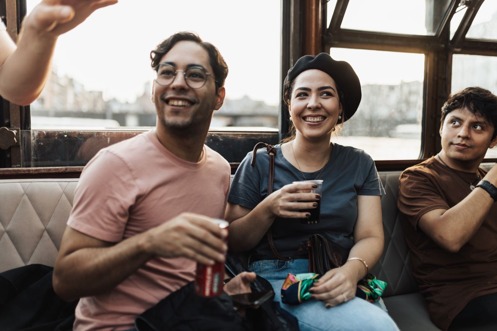 Three friends laughing with drinks on a boat, deciding which cruise is the most fun